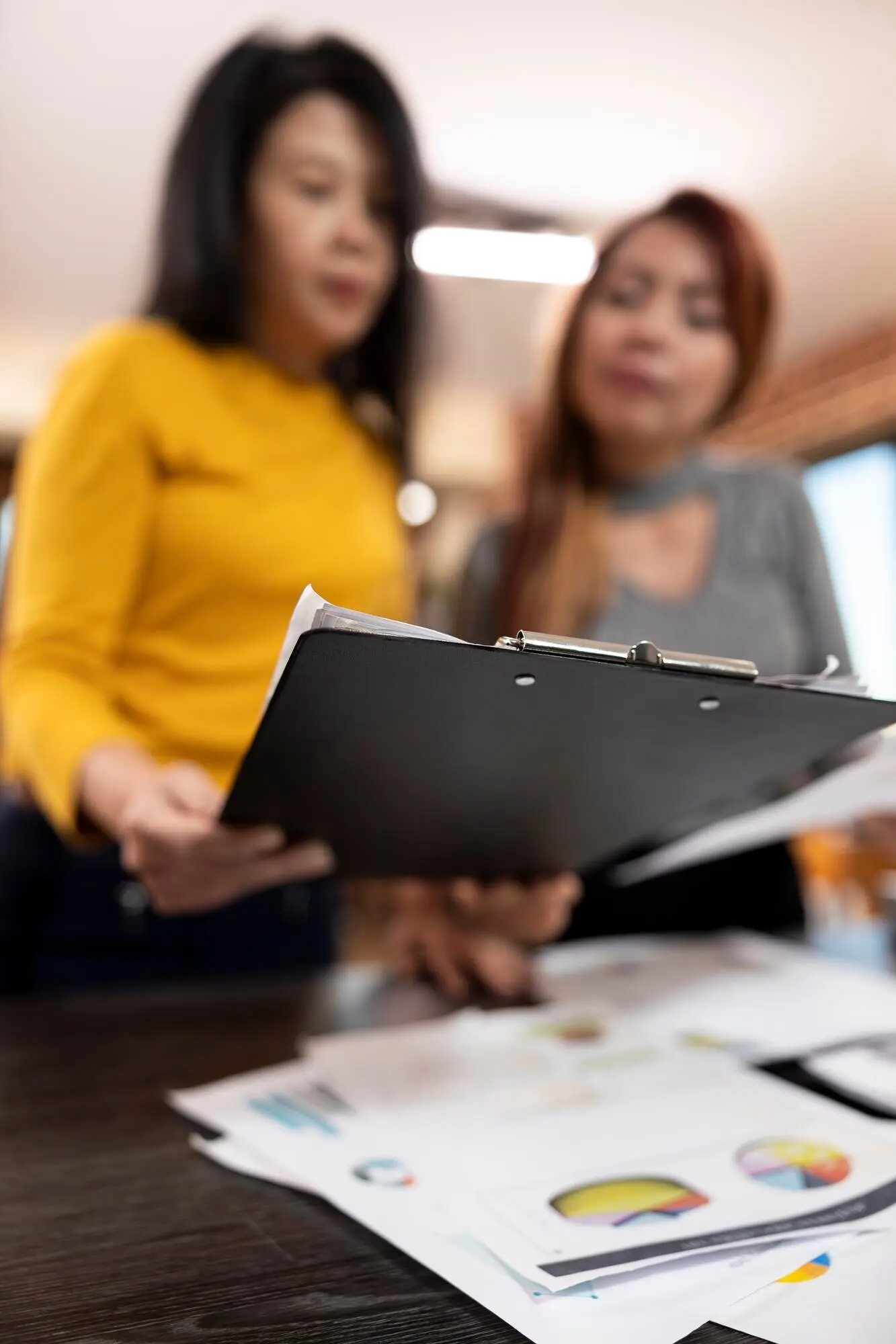 Женщины азиатского происхождения изучают деловые отчеты.