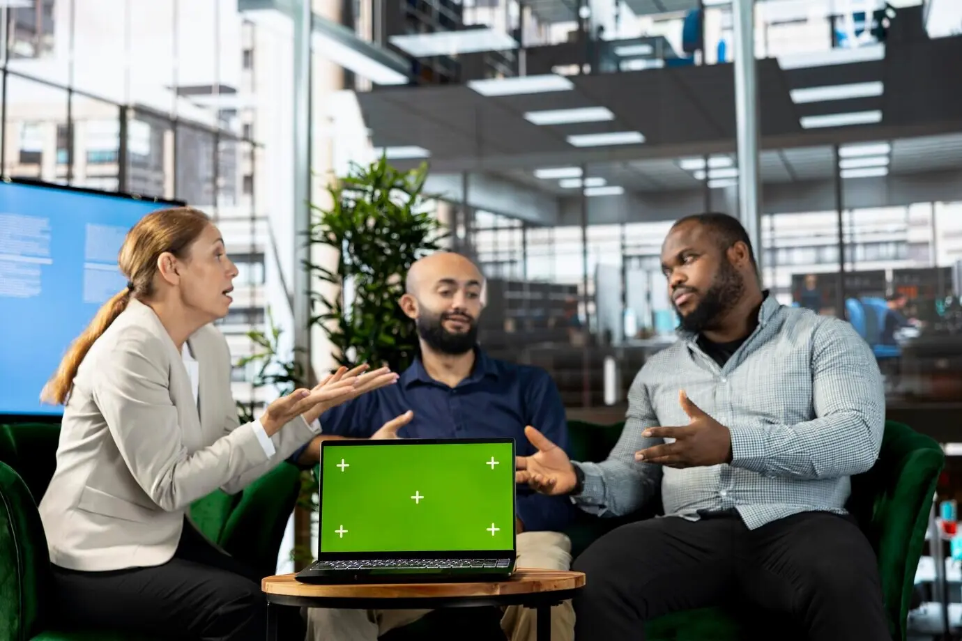 Изолированный экран планшета рядом с сотрудниками, просматривающими исследовательскую документацию.